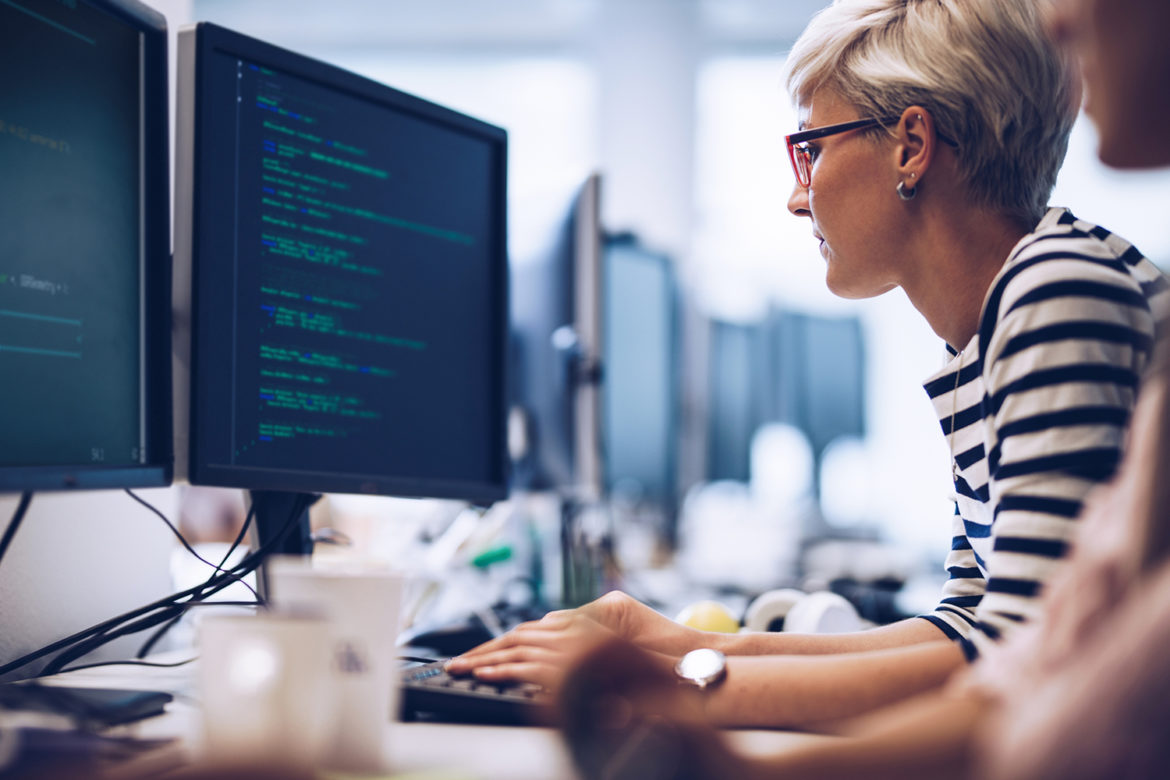 Profile view of young female programmer working on computer software in the office.