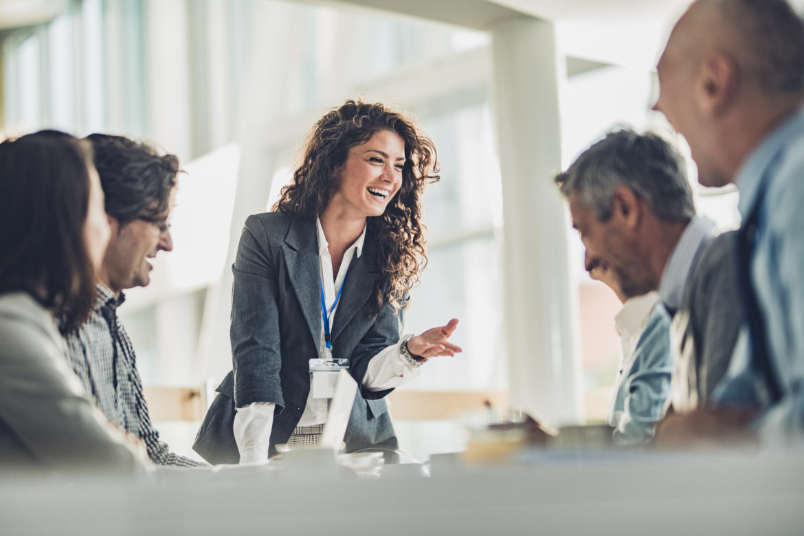 Happy female leader talking to her colleagues on a business meeting in the office.